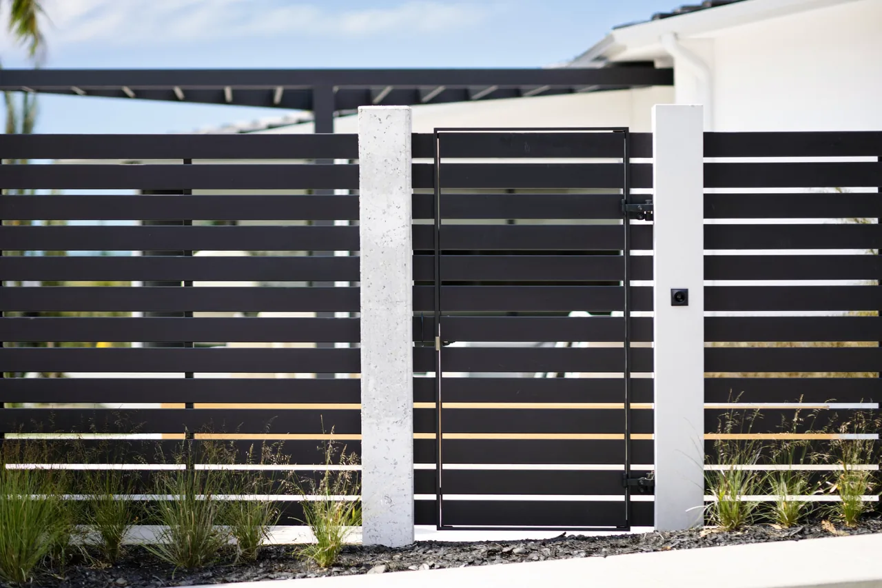 Matte black aluminium slat privacy fence and matching gate at a modern home