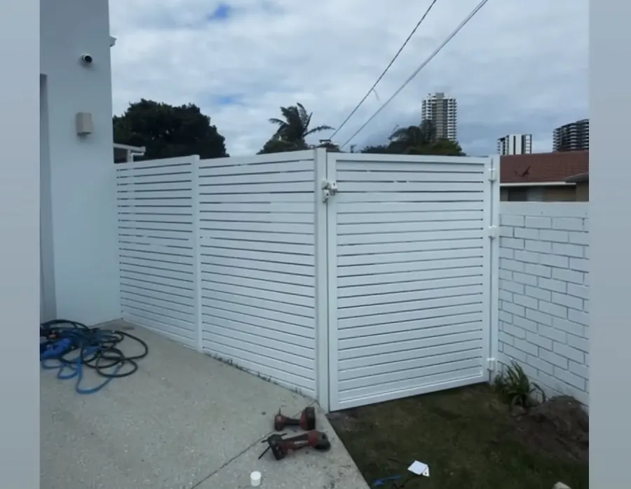 White powder-coated aluminium horizontal slat privacy screen and gate in a courtyard