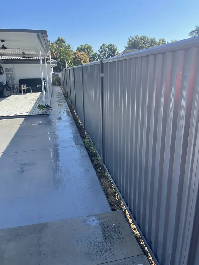 Grey Colorbond fence running alongside a new concrete driveway