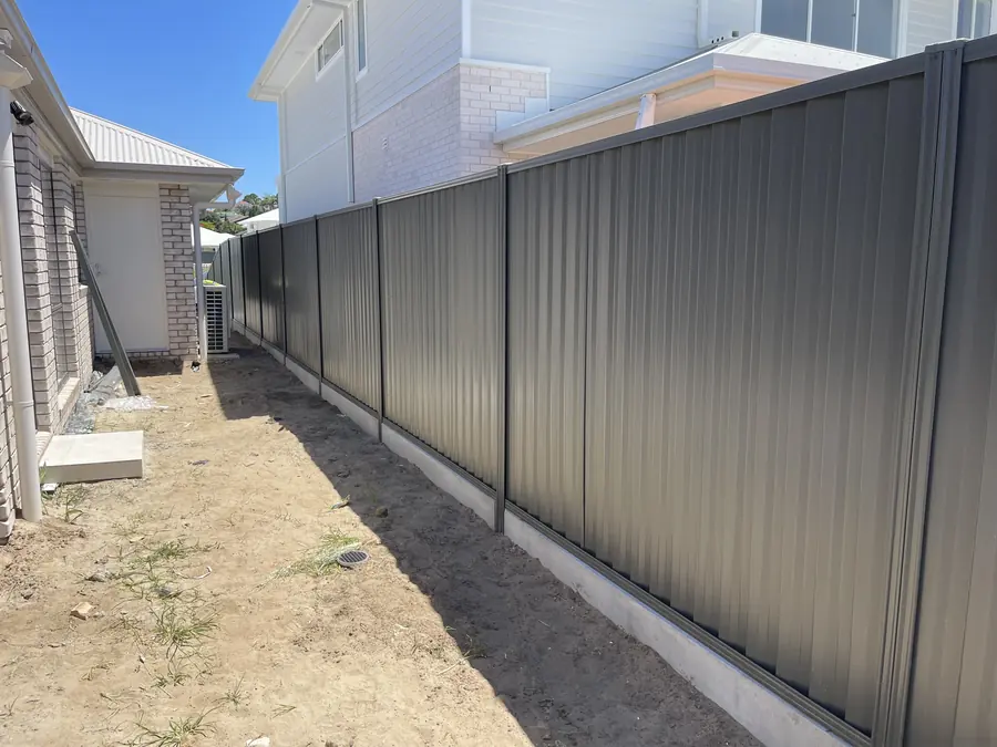 Grey Colorbond fence along a narrow side boundary on a concrete strip footing