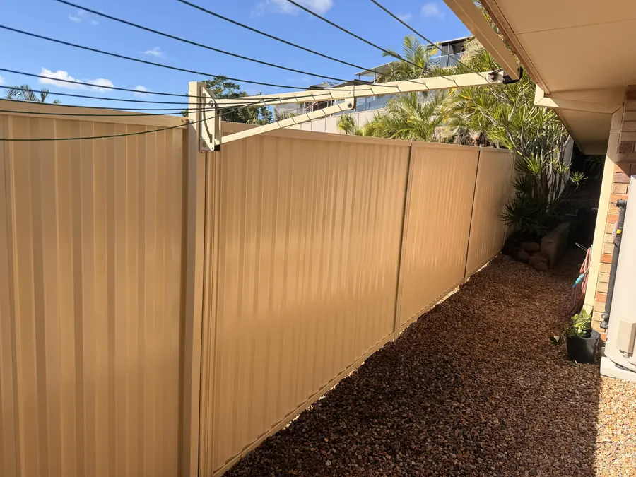 Cream Colorbond fence along a side path with a rotary clothesline