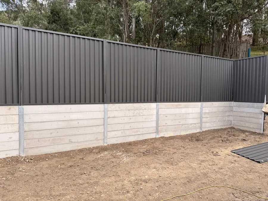 Grey concrete sleeper retaining wall with a charcoal Colorbond fence above