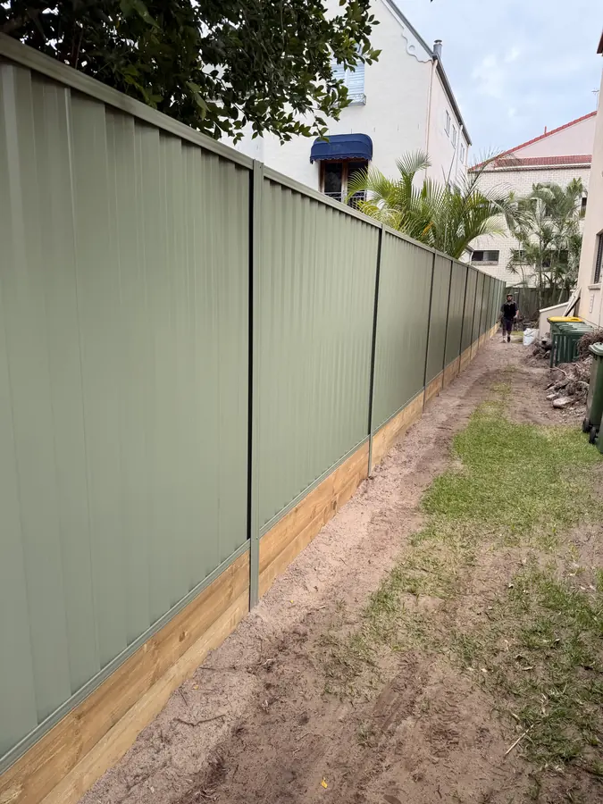 Pale green Colorbond fence on a treated pine sleeper retaining wall down a side boundary