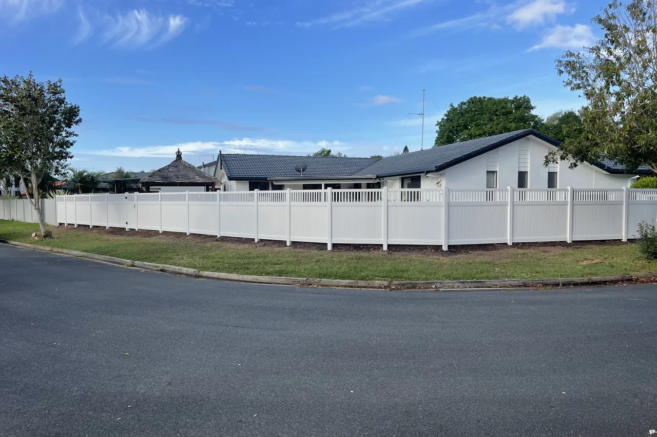 White PVC privacy fence with picket top wrapping a corner block frontage