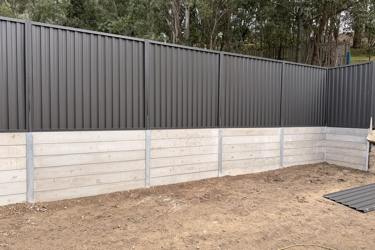 Grey concrete sleeper retaining wall with a charcoal Colorbond fence above